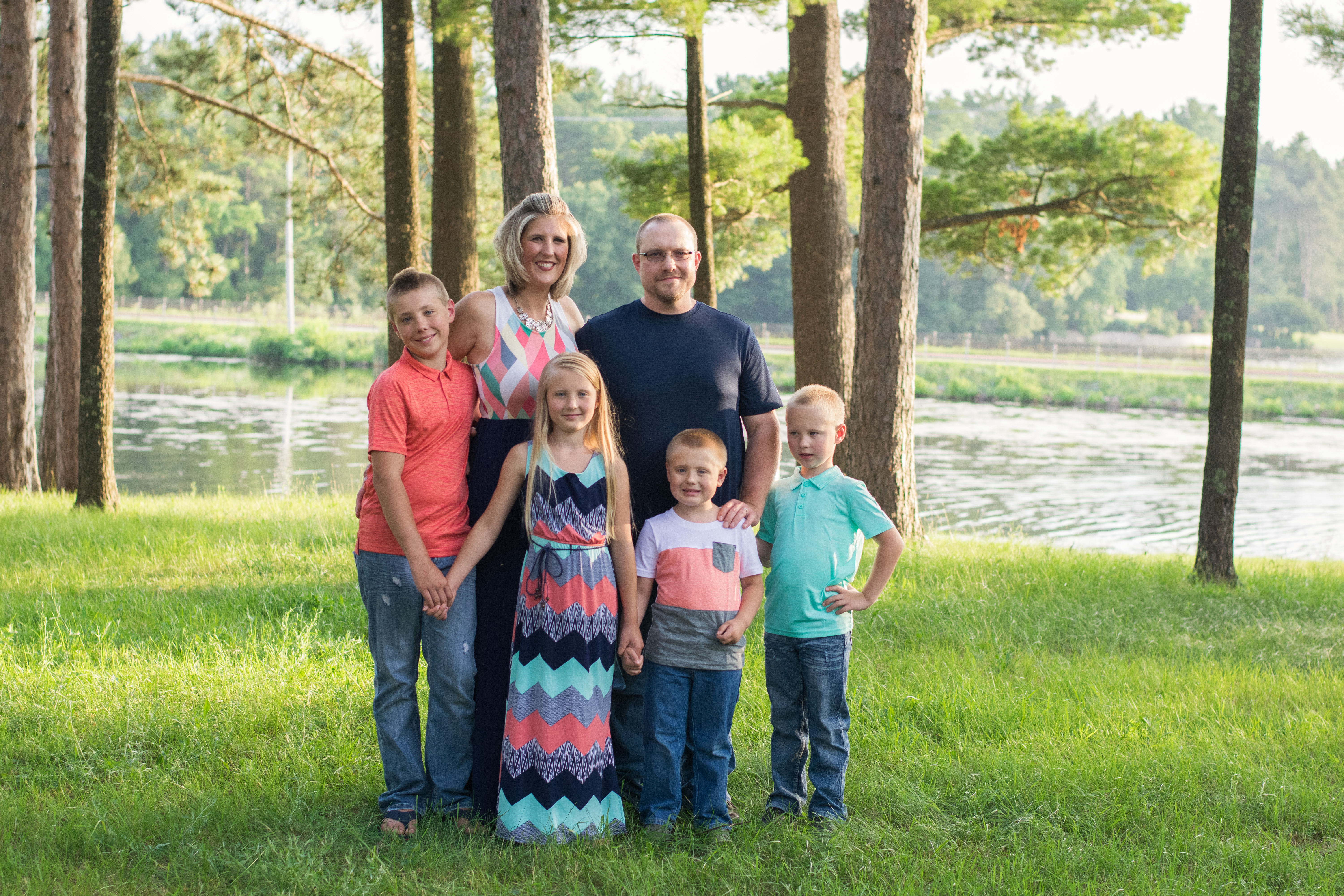 The Wrycza Family standing in front of the river with trees in the background.